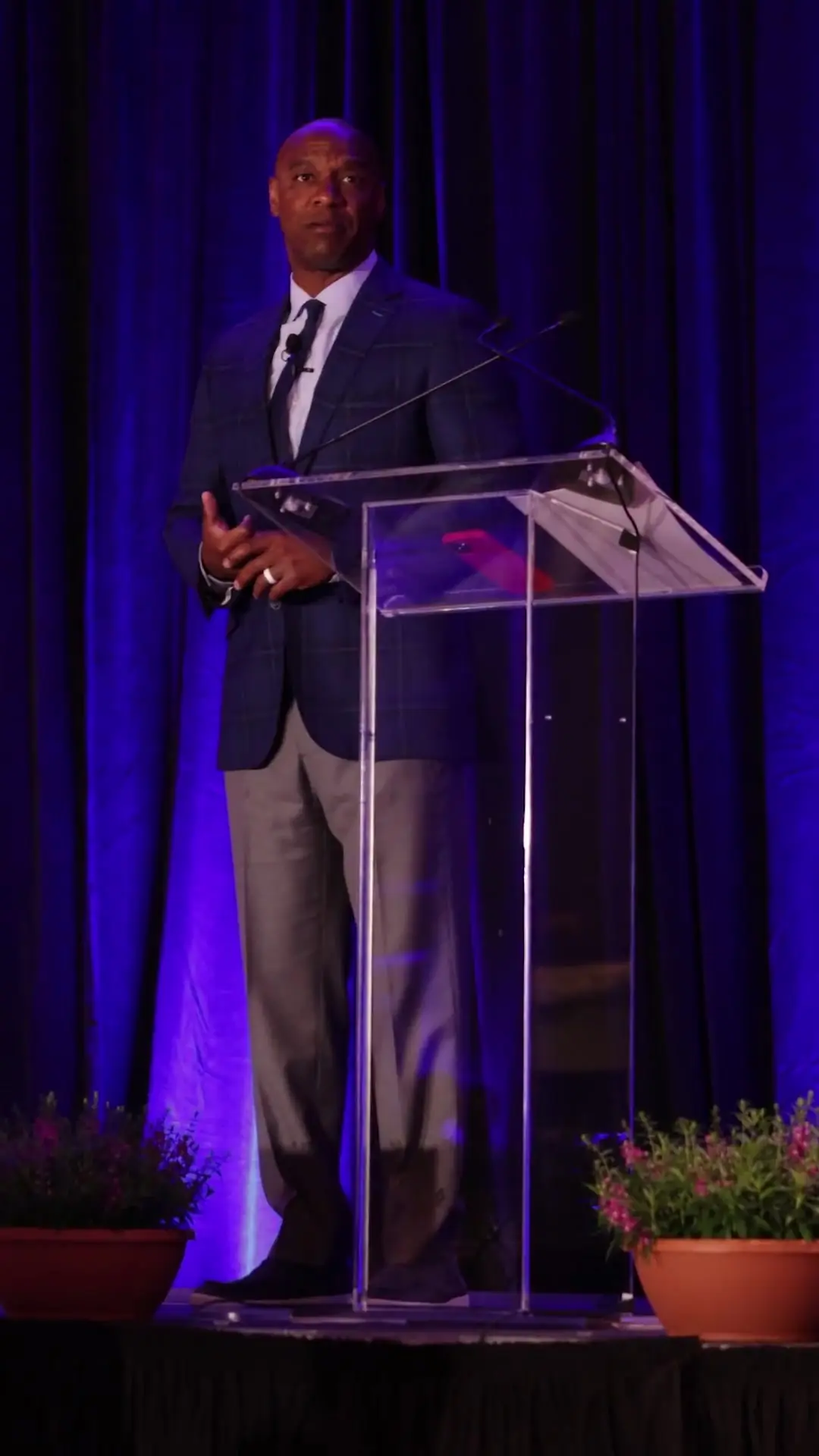 Jarrett Payton speaking at a podium in front of a blue curtain