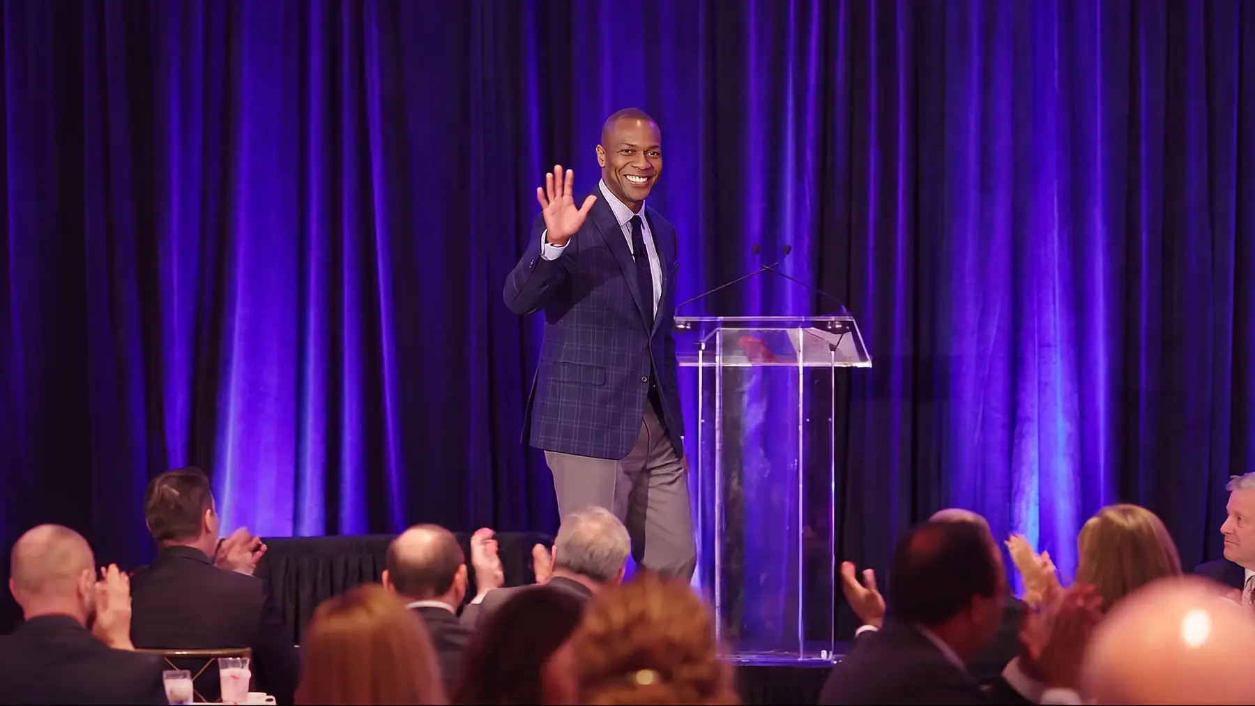 Jarrett Payton walks onto the stage and waves as the ballroom audience applauds